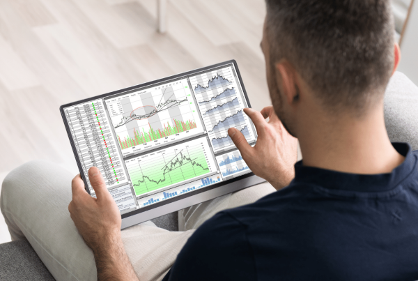 Man analyzing stock market data on a tablet, featuring various financial charts and graphs, relevant to nonprofit stock donation strategies.