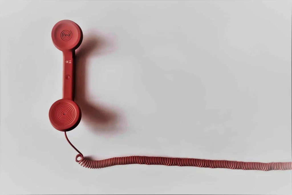 Red telephone receiver with coiled cord on a light background, symbolizing communication for stock donation outreach strategies.